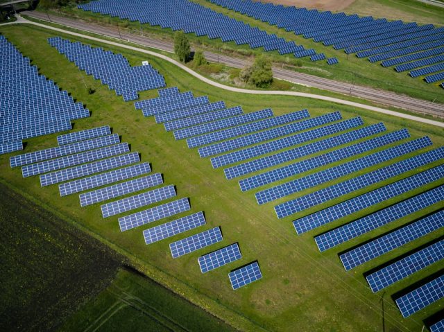 A vast field of solar panels stretches to the horizon under a bright sky, symbolizing China's record-breaking one terawatt solar capacity.