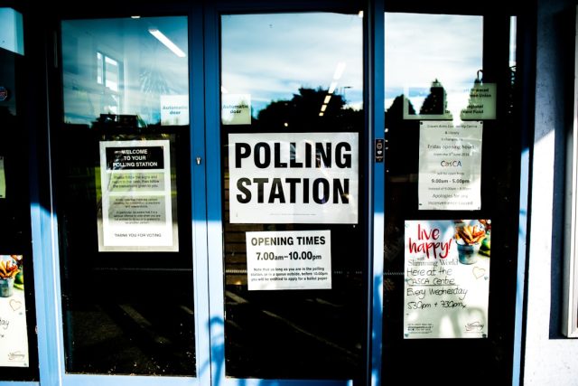 Voters walk past a Los Angeles polling station with a sign for the June 2 mayoral election.