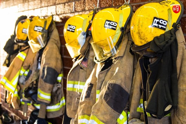 Firefighters work outside a charred three-story guesthouse after an overnight blaze that left ten dead.