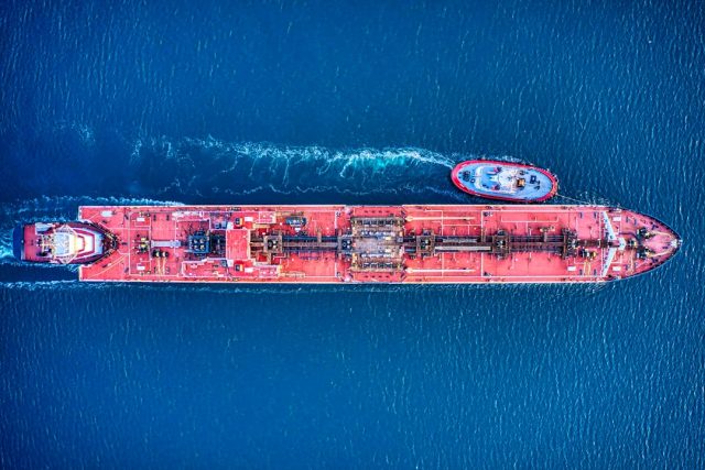 Two burning tankers billow black smoke near an Iraqi port as rescue boats approach the stricken vessels.