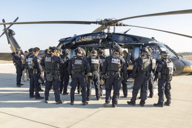 Emergency vehicles and responders outside a modern tactical training facility after a blast during SWAT drills.