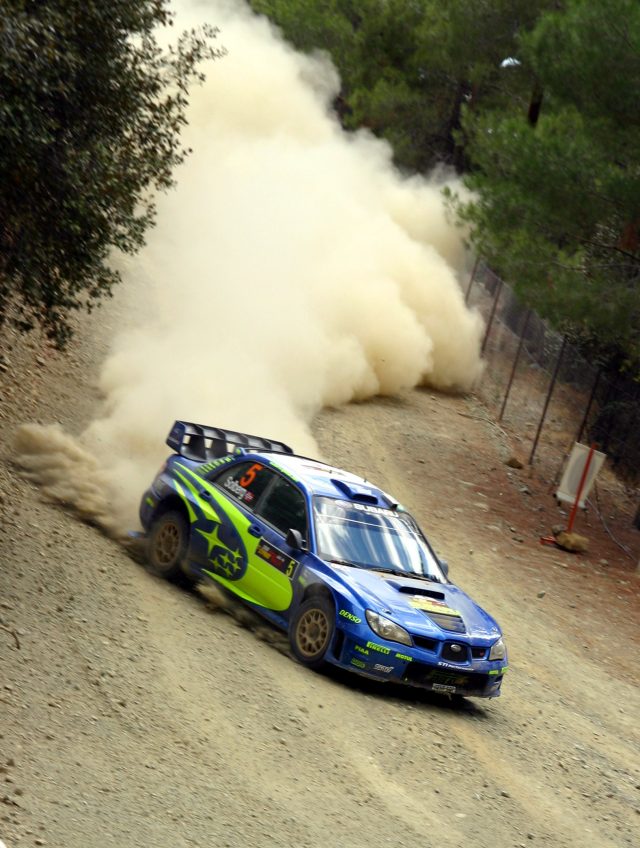 Rally car slides off forest road as spectators scramble for safety amid dust and debris
