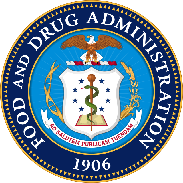 FDA officials and Gilead executives shake hands behind a backdrop displaying the Yeztugo logo at the drug approval announcement.