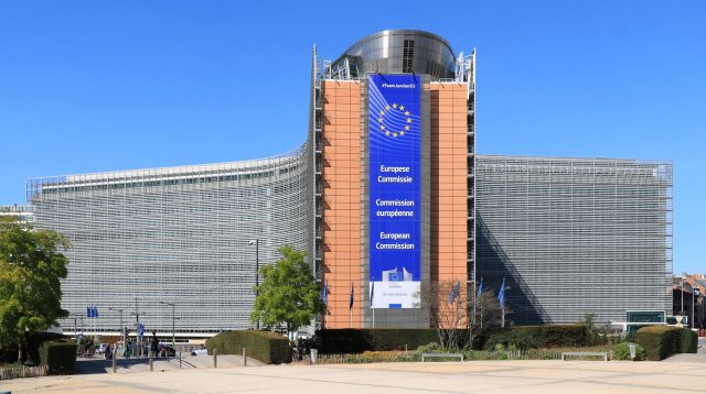European Commission headquarters in Brussels, with a digital display showing the X logo crossed out