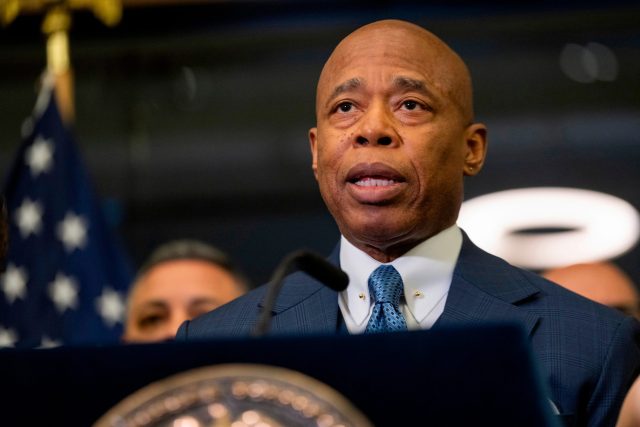 New York City Mayor Eric Adams speaking at a press conference with NYPD officers in the background