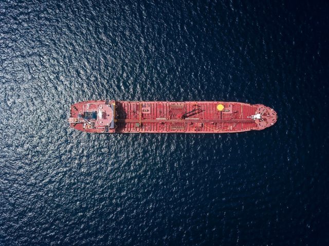 A container ship loaded with cargo arrives at a U.S. port, representing trade flows affected by tariff manipulation.