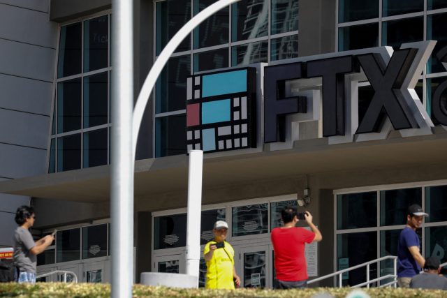 Empty FTX trading floor desks lit by blue screens as staff exit after bankruptcy filing