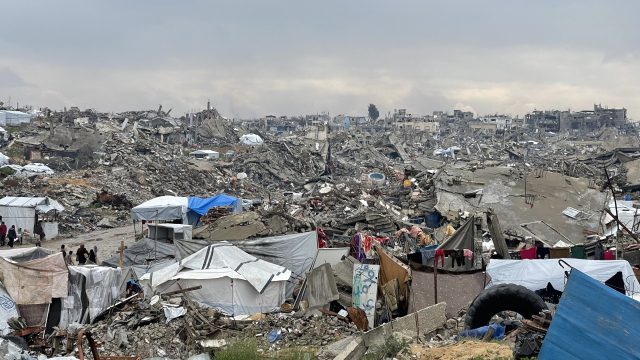 Destroyed buildings and rubble in Gaza City after Israeli airstrikes, with smoke rising in the background