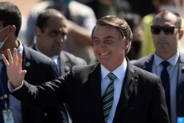 Jair Bolsonaro stands before the Brazilian flag at the end of his presidential term, July 2023.