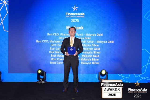 Maybank Investment Bank executives holding award trophies at a formal ceremony in Kuala Lumpur.
