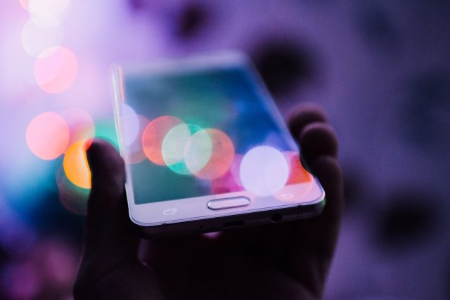 A person holds an iPhone displaying the ChatGPT app interface with a text input field and response area.