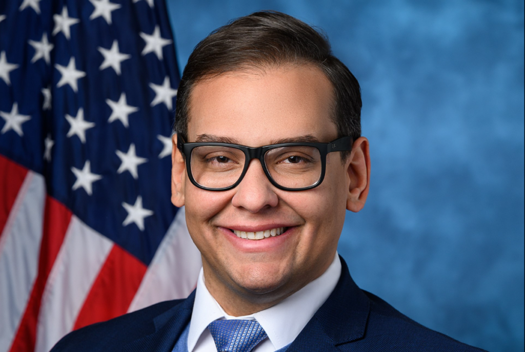Rep. George Santos stands at a Capitol Hill podium as reporters question him about falsified biography claims.